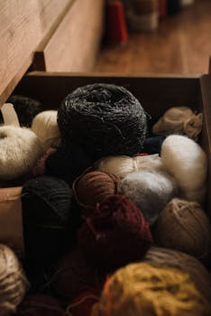 A textured close-up of assorted yarn rolls stored neatly in a wooden drawer.
