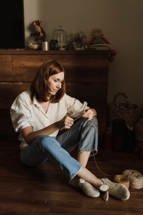 Frau Im Weißen Hemd Und In Den Blauen Jeans, Die Auf Boden Sitzen