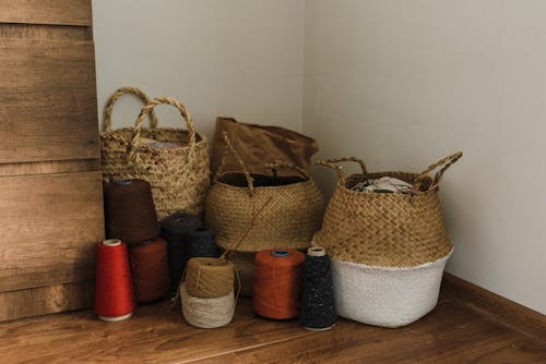 Brown Woven Baskets and Yarn Roles on Wooden Floor