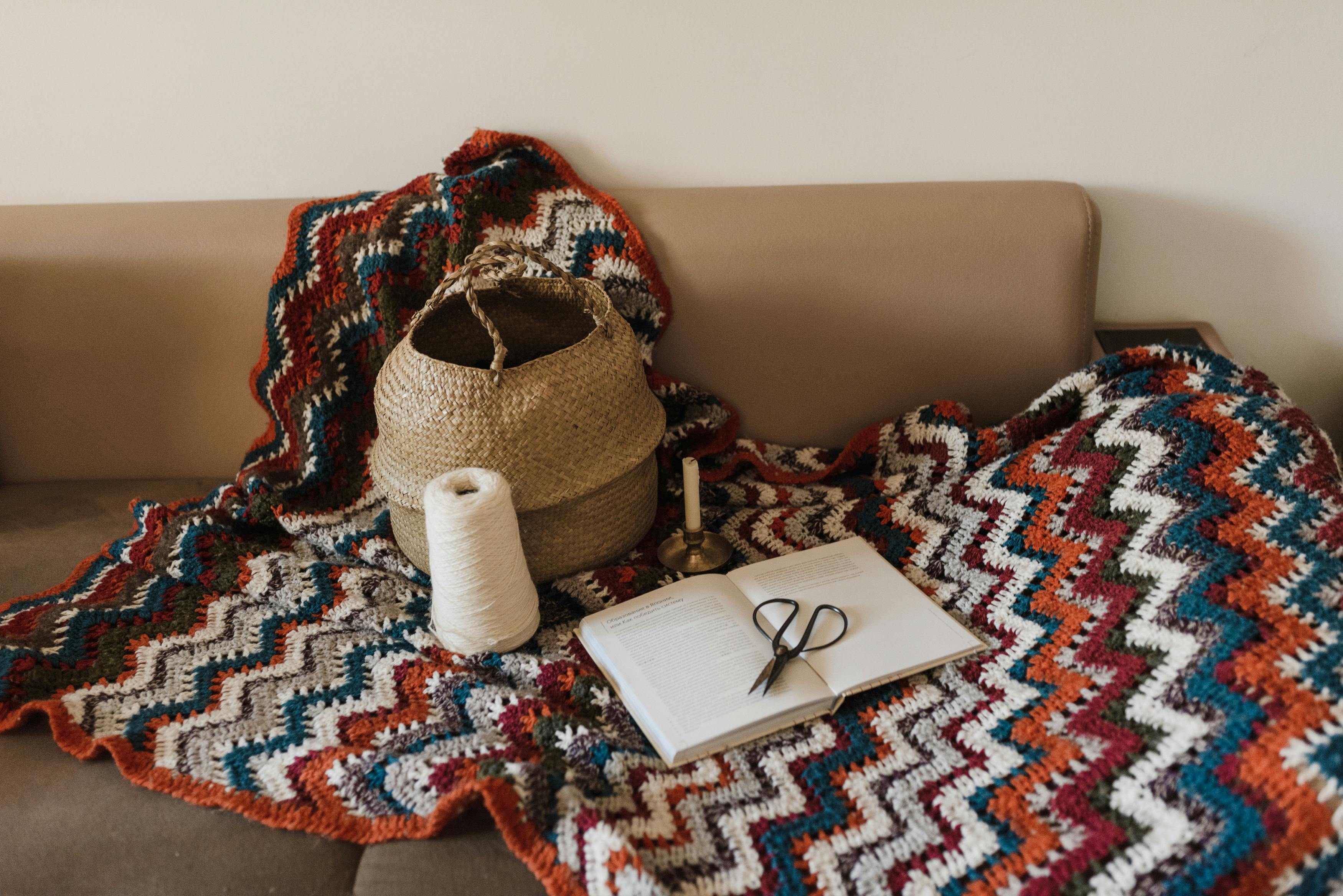 Colorful handmade crochet blanket with crafting tools on a cozy couch.