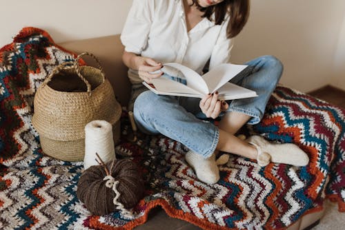 Frau Im Weißen Langarmhemd Und In Den Blauen Jeans, Die Auf Braunem Und Weißem Textil Sitzen