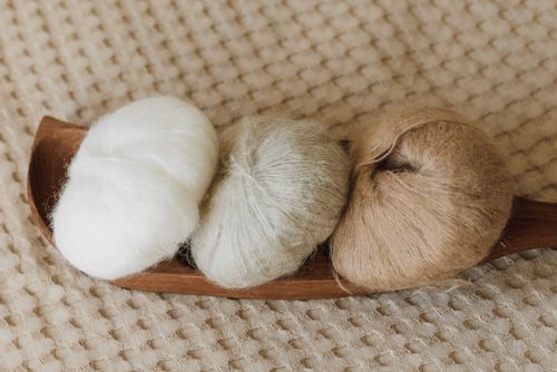 Free Three wool yarn balls in neutral tones placed on an elegant wooden tray. Stock Photo
