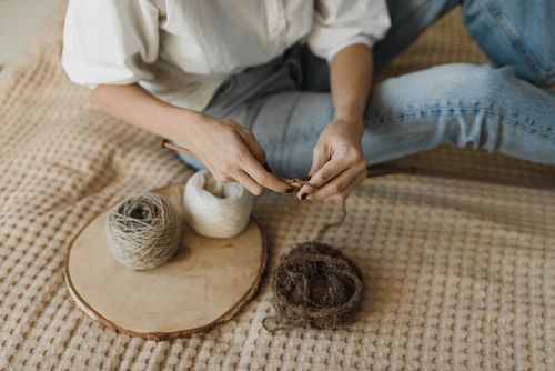Free A woman is knitting with needles and yarn rolls placed on a wooden board indoors. Stock Photo
