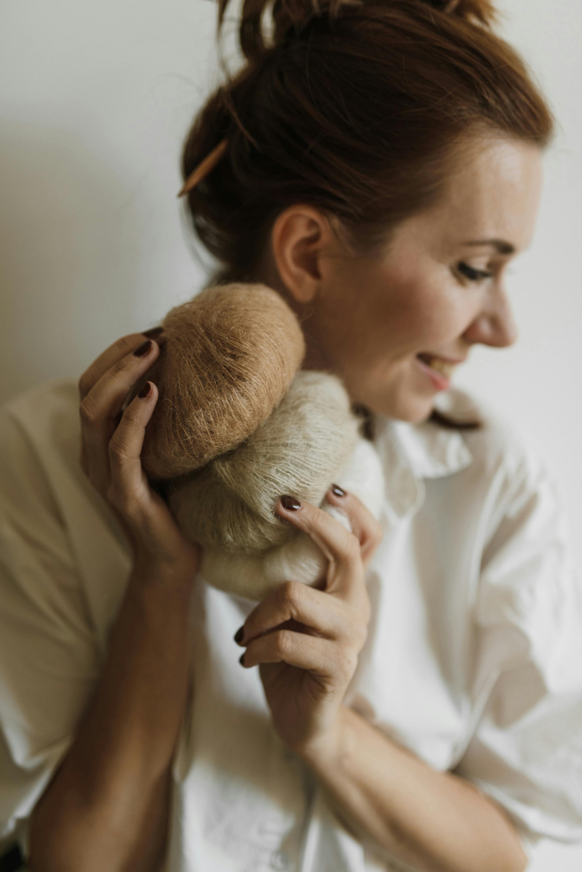 Smiling woman holding soft yarn in cozy home setting, perfect for knitting enthusiasts.