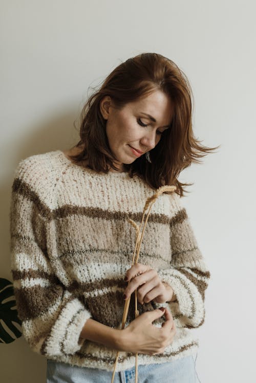 A Woman in Knit Wear Holding Stalks of Wheat
