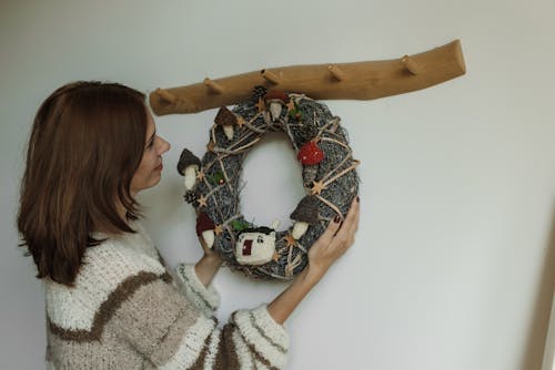 A Woman Holding a Christmas Wreath Hanging on a Wooden Rack