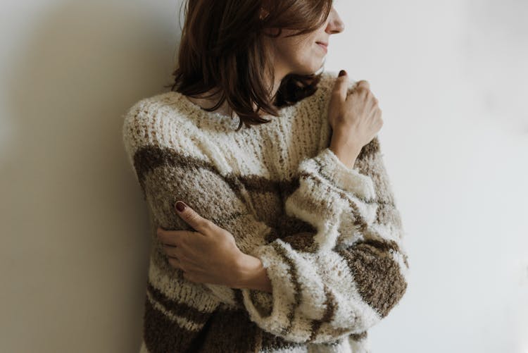 A Woman In Knit Sweater Hugging Self