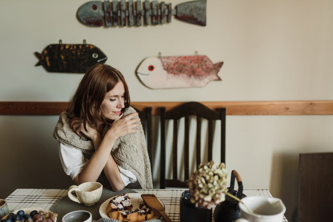 A Woman Sitting at a Table with a Mug and Food