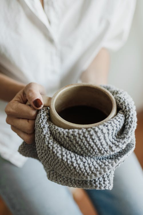 Free A Person Holding a Ceramic Mug Wrapped with Knitted Cloth Stock Photo