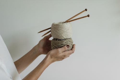 Free Hands holding yarn and knitting needles, embracing the art of knitting. Stock Photo