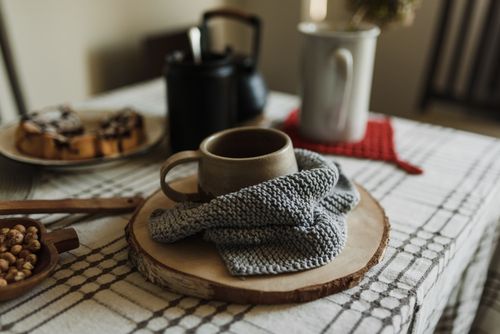Free A warm and cozy table setup featuring a ceramic mug, knitted cloth, and breakfast pastries. Stock Photo