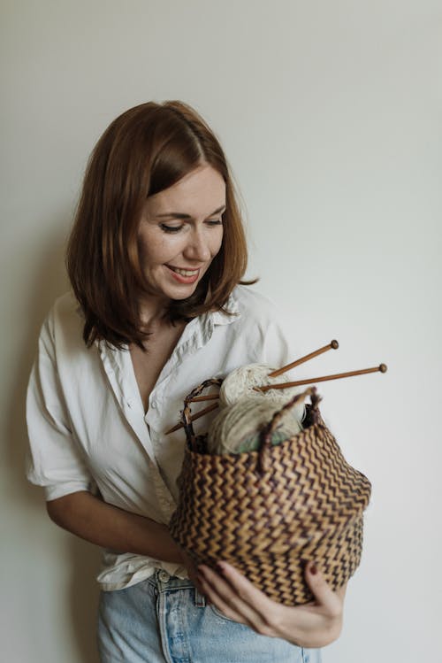 Woman in White Shirt Holding Basket with Knitting Needles