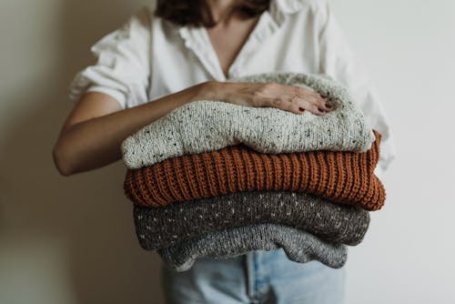 Woman Holding Pile of Knitted Sweaters