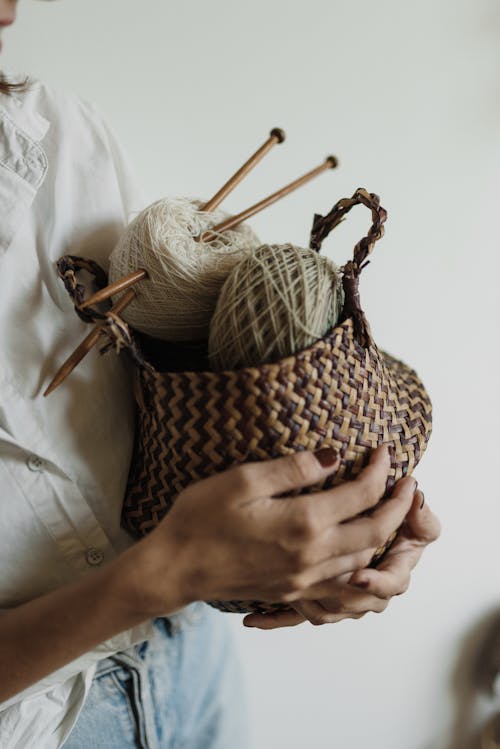 Person Holding a Woven Basket with Knitting Kit
