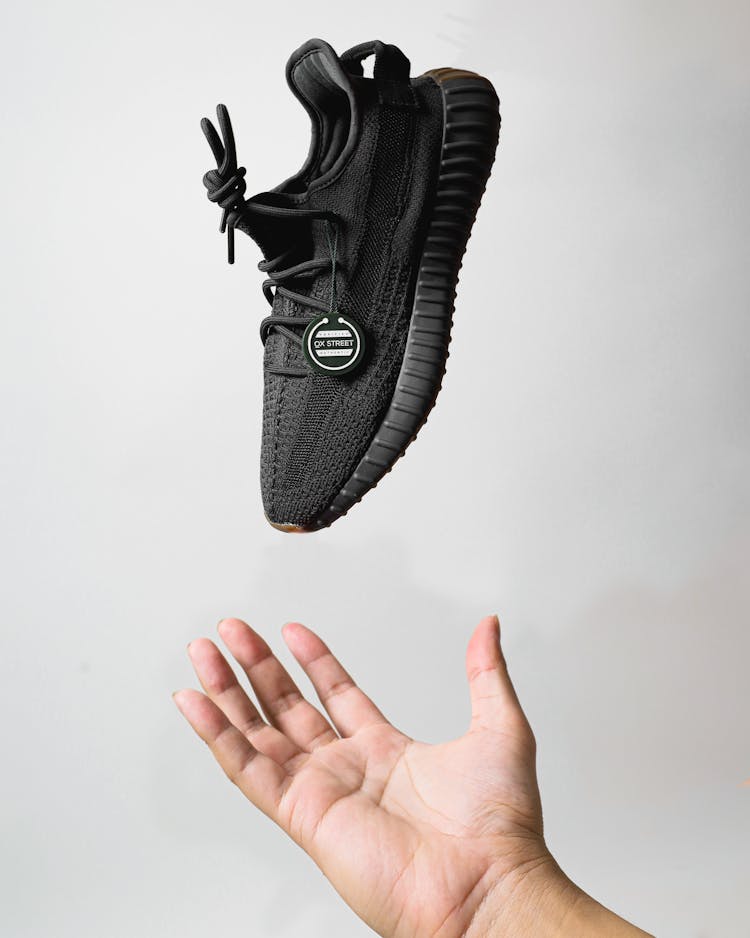 Hand Catching A Black Sneaker Shoe 