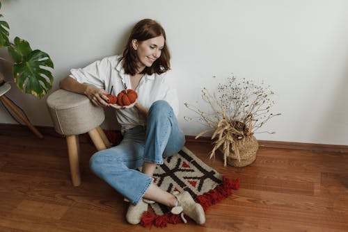 Woman Wearing White Long Sleeve Sitting on a Rug