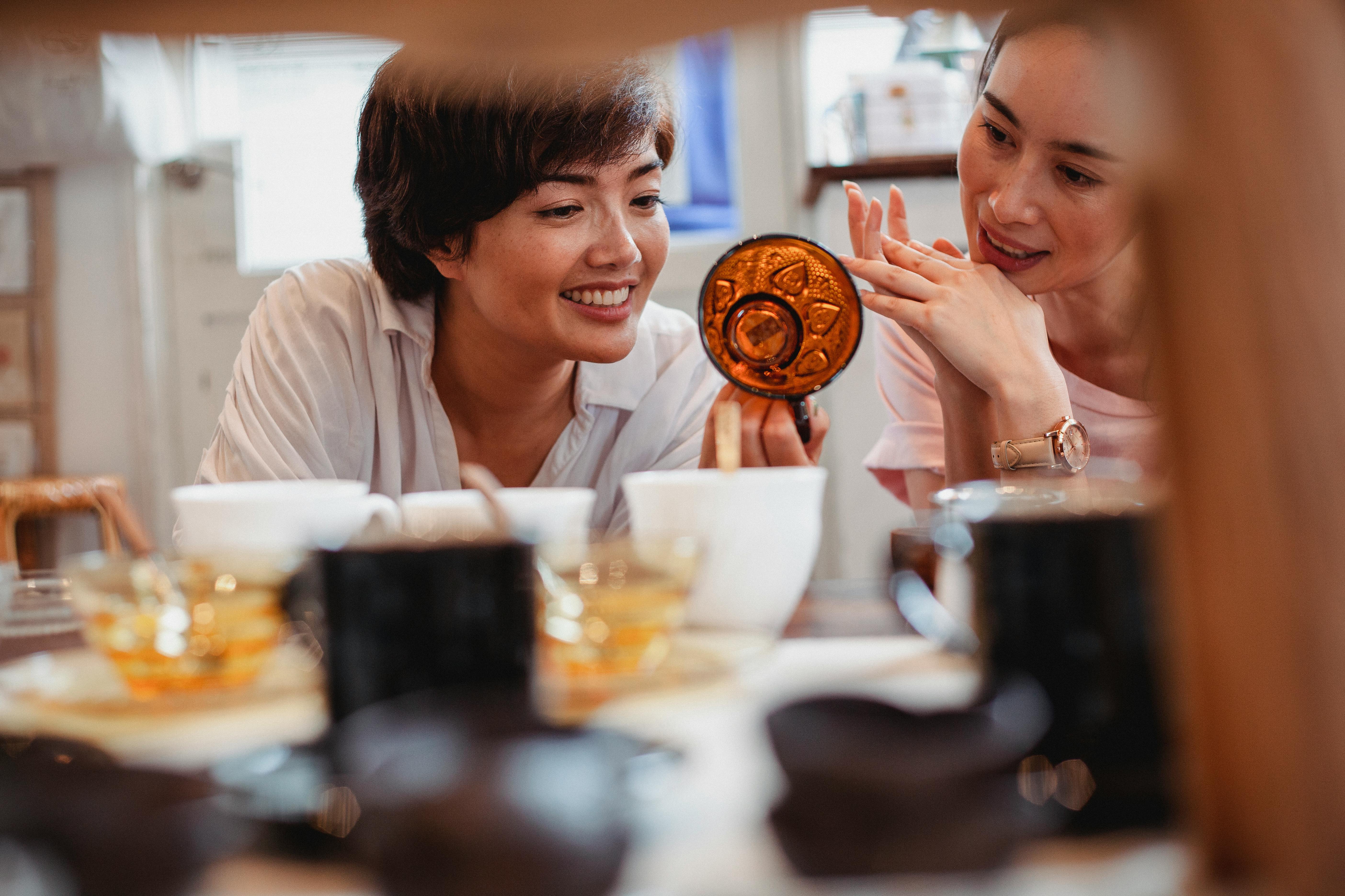 delighted young asian women choosing cups in modern shop