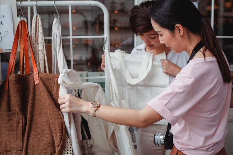 Trendy Young Asian Women Choosing Cotton Bags In Fashion Boutique