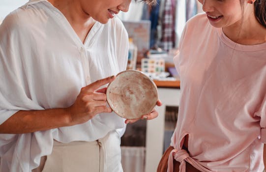 Two women happily browse and select ceramic dishware in a trendy shop.