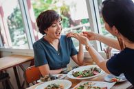 Crop woman feeding pizza to friend