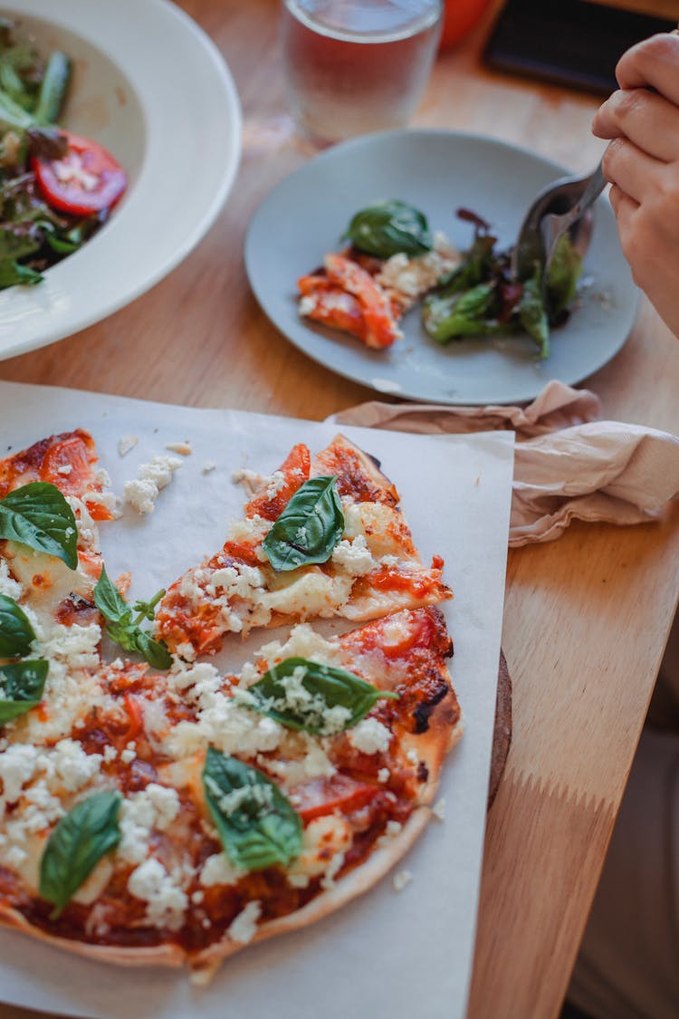 Crop Person At Table With Pizza And Salad