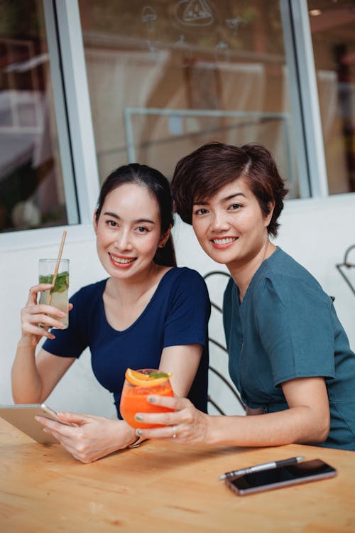 Charismatic Asian women with cocktails at table