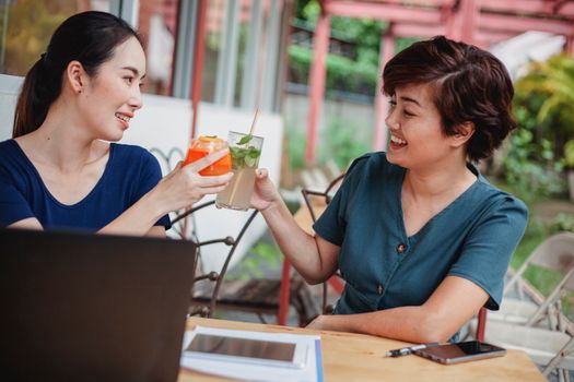 在户外商务会议上，两位女士碰杯，象征着合作