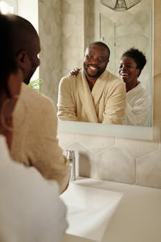 Smiling couple in bathrobes reflecting in mirror during their morning routine.