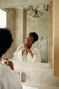 African American woman in a bathroom admiring her reflection with a smile.