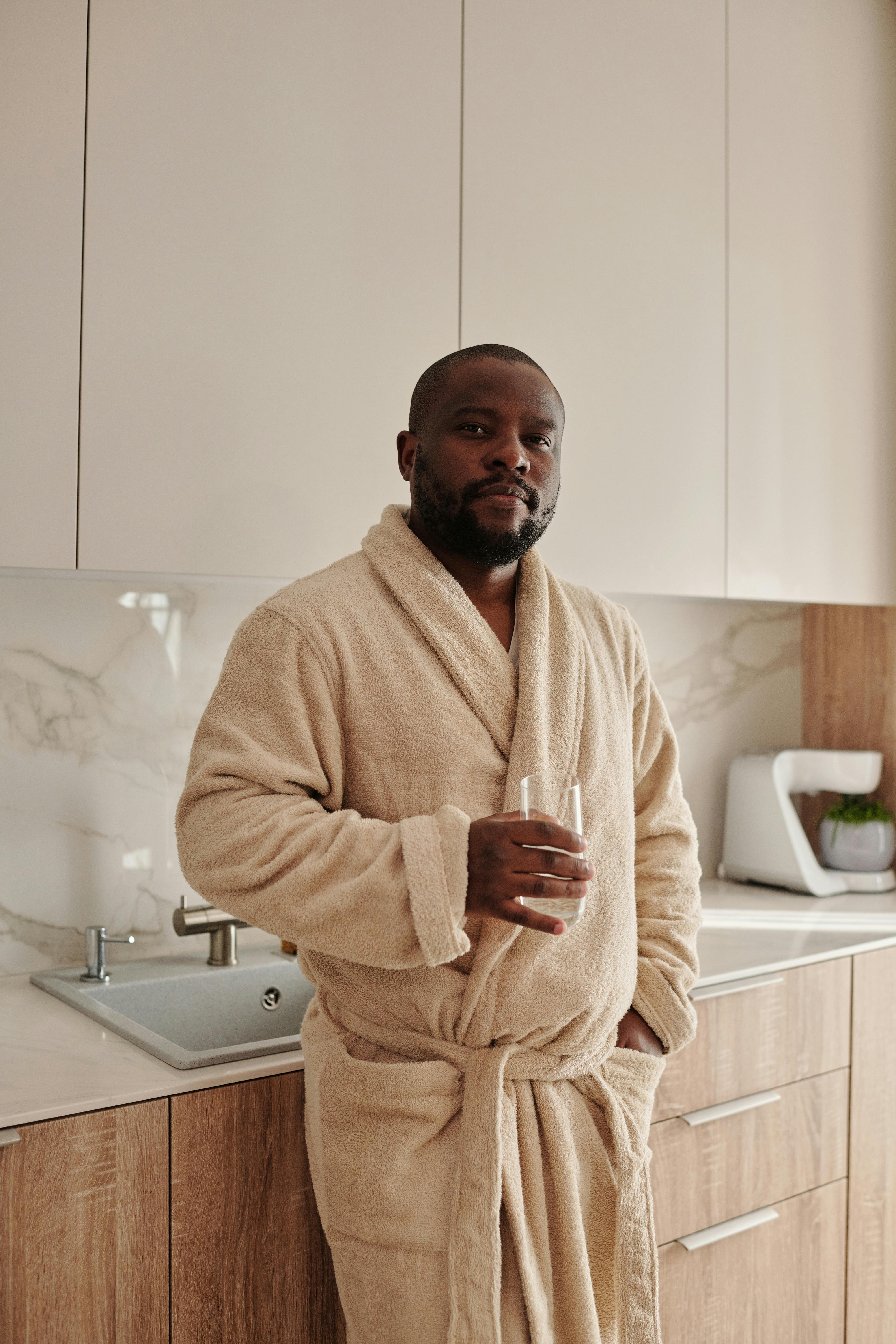 man wearing an bathrobe holding a glass of water