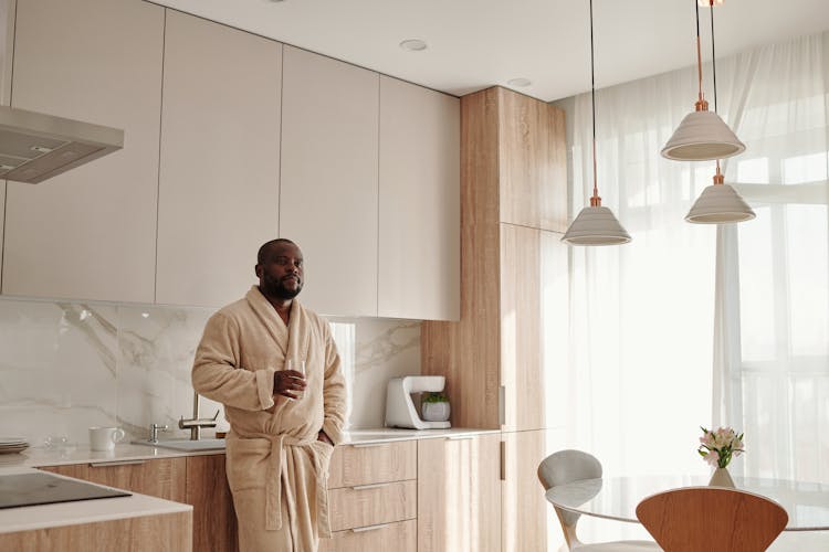 Man In Beige Bathrobe Leaning On Kitchen Counter