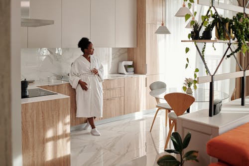 Woman in White Bathrobe Leaning on Kitchen Counter