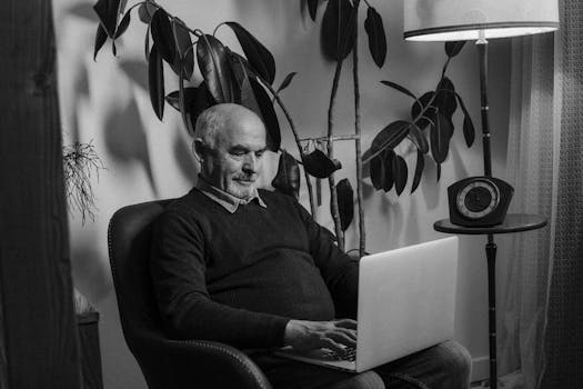 Senior adult man working on a laptop in a cozy setting, highlighting remote work lifestyle.