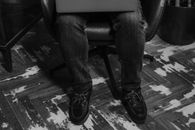 Man in Black Pants and Black Leather Shoes Sitting on Black Leather Chair