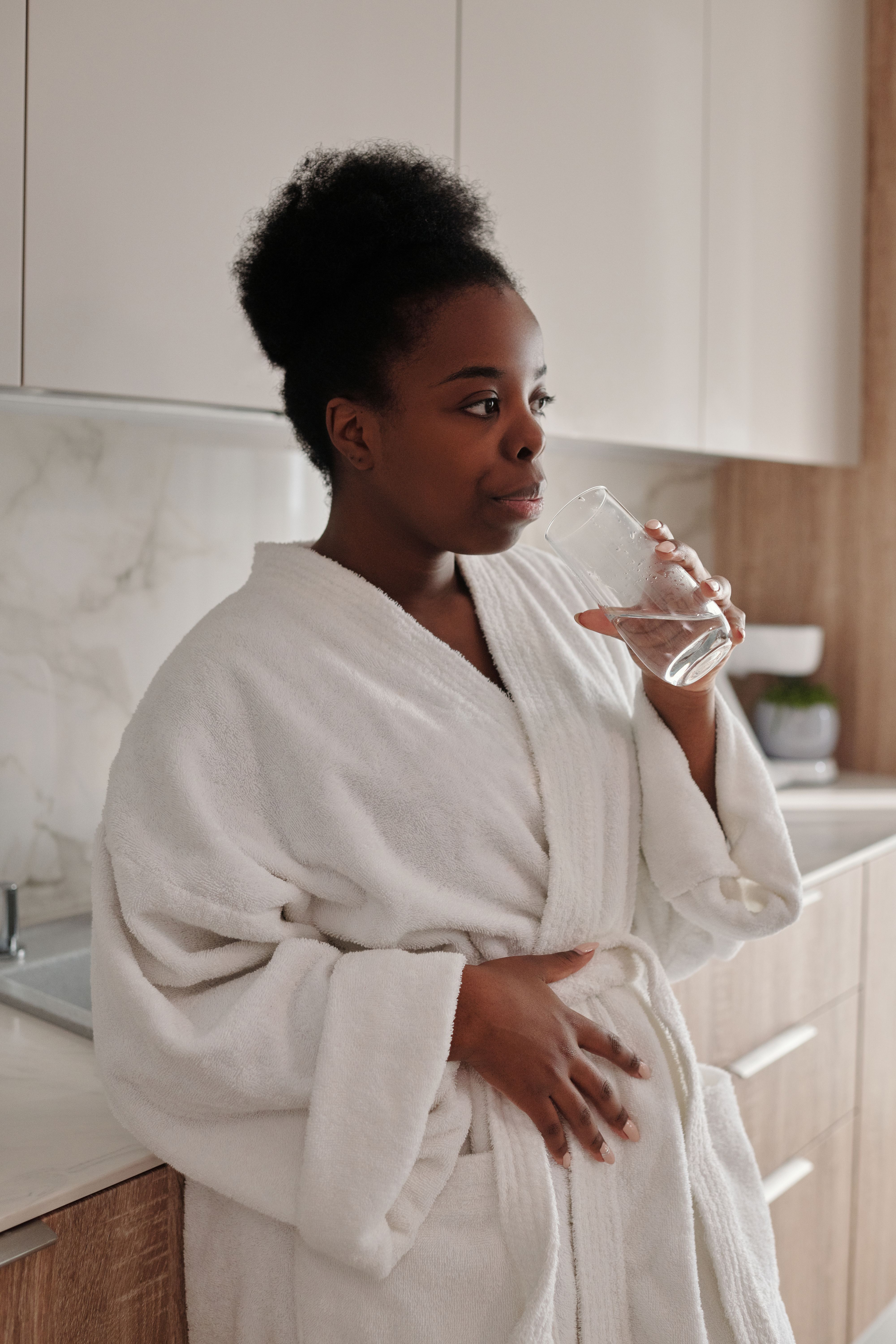 Femme buvant un verre d'eau le matin pour s'hydrater dès le réveil