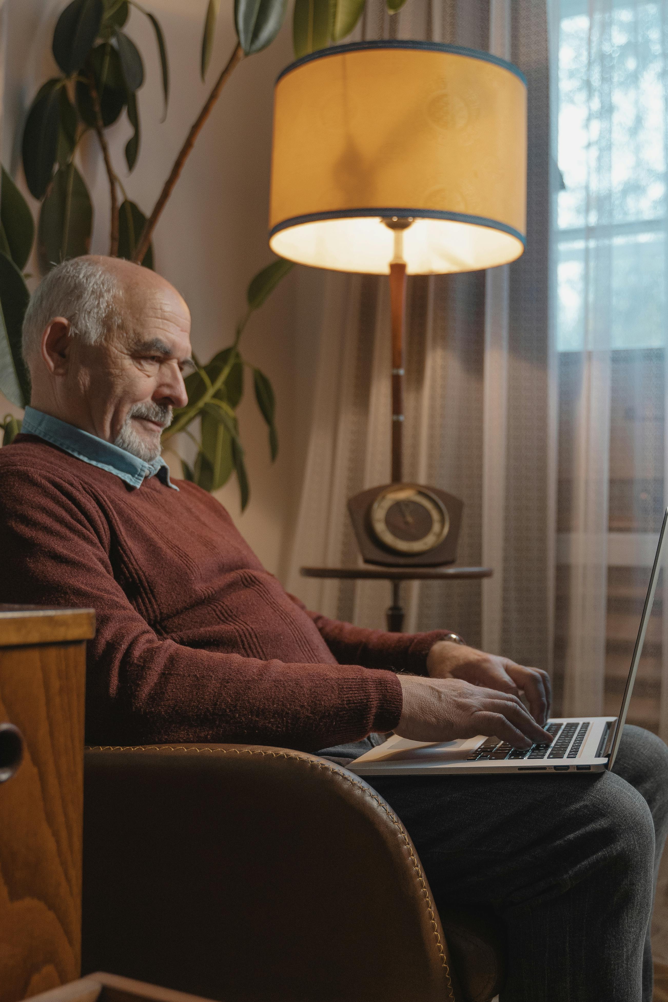 elderly man in brown sweater using laptop