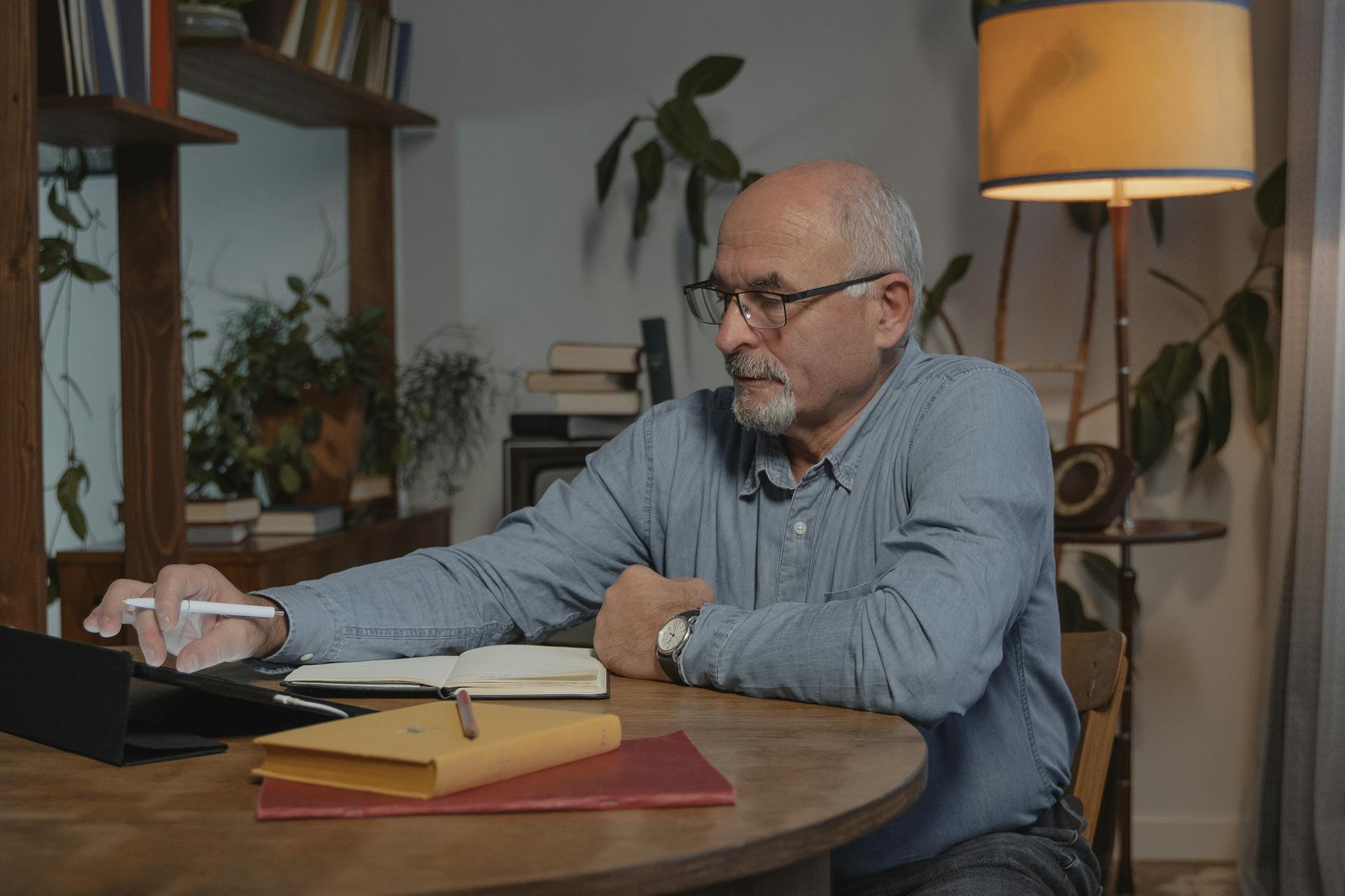 Senior man working on a tablet in a cozy home office setting.