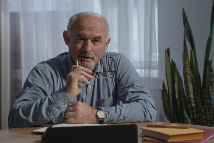 Elderly Man Thinking While Biting Eyeglasses