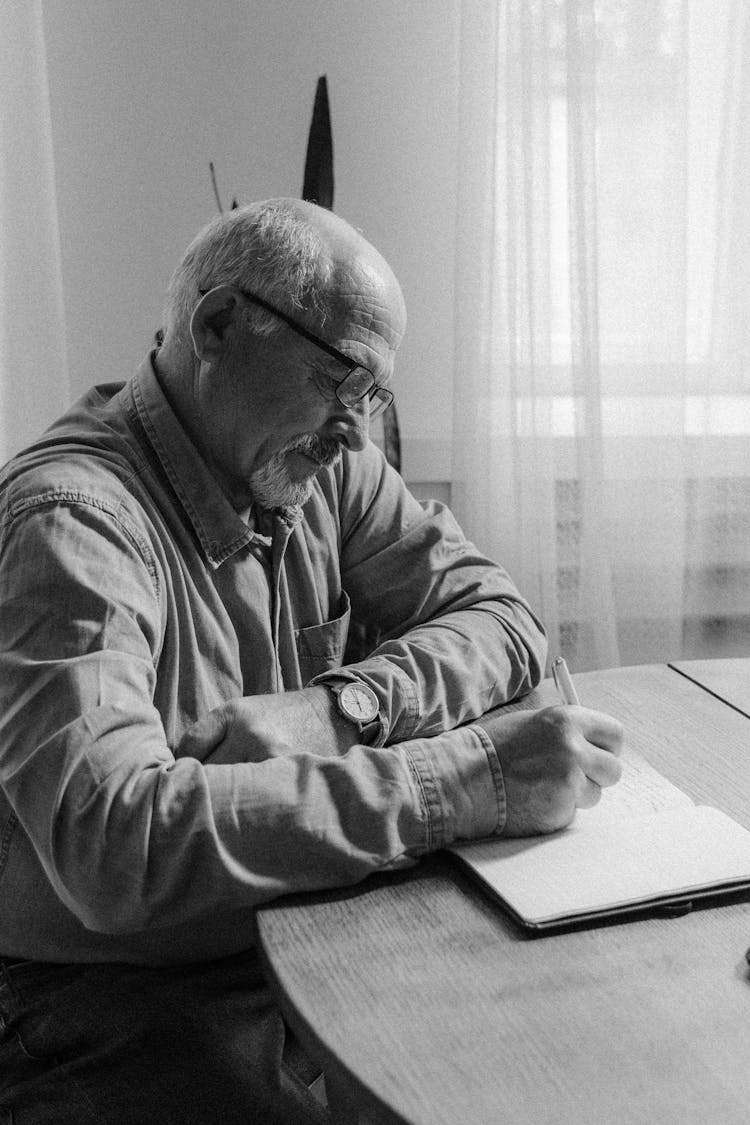 Grayscale Photo Of A Man Writing Notes 