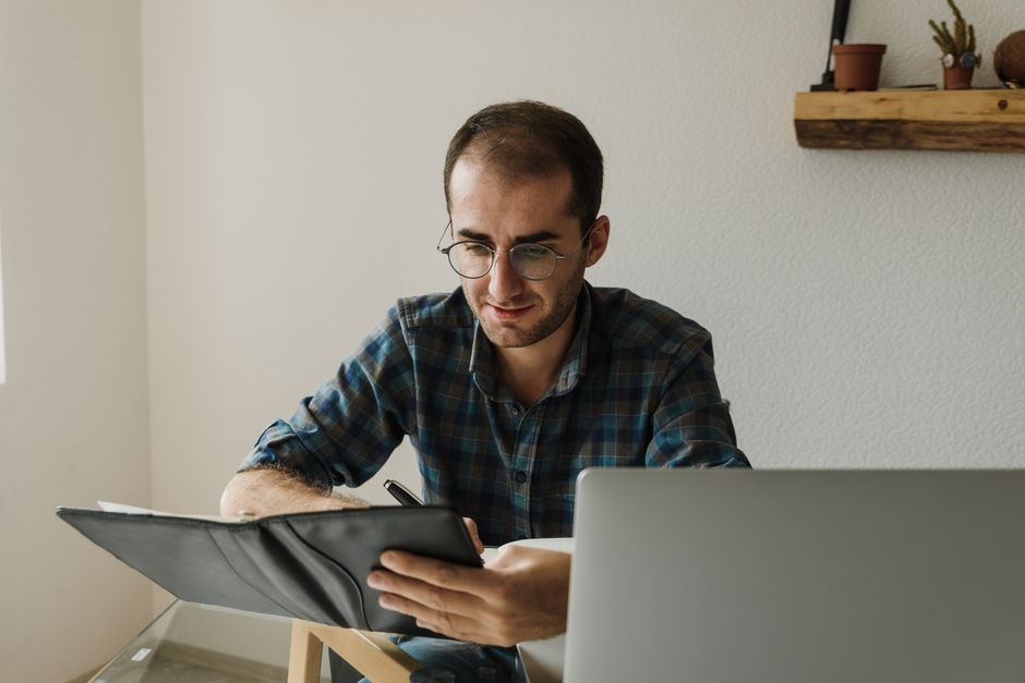 A man taking notes while comparing plans online, a practical look at health insurance for self employed men