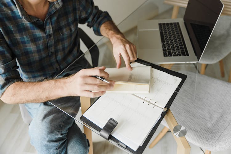 A Person's Hands Closing A Notebook