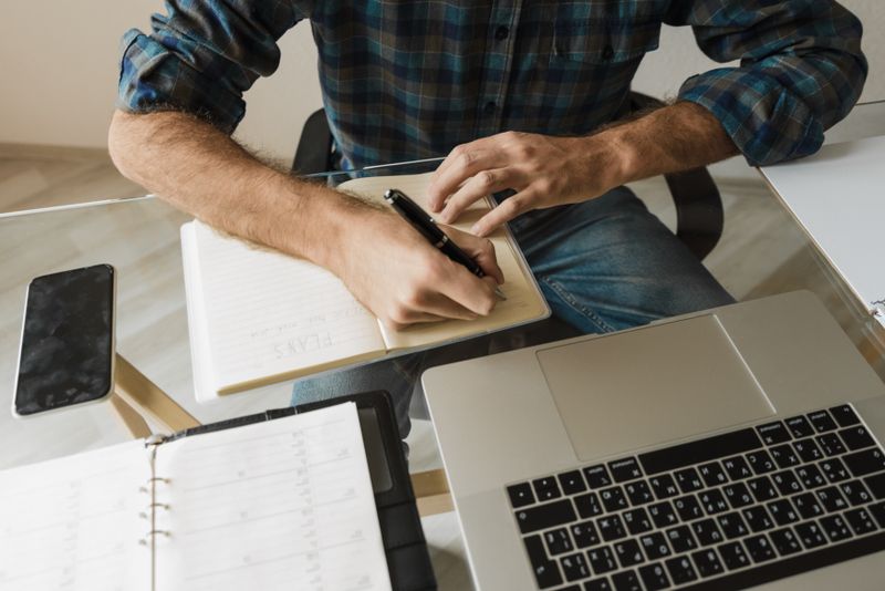 a person writing notes at a desk in morning light