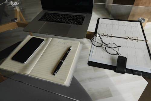 免费 Macbook Pro在白色打印机纸上的黑色和银色单击笔旁边 素材图片