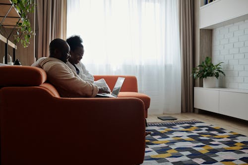 Photo of a Couple Watching while Sitting on a Sofa