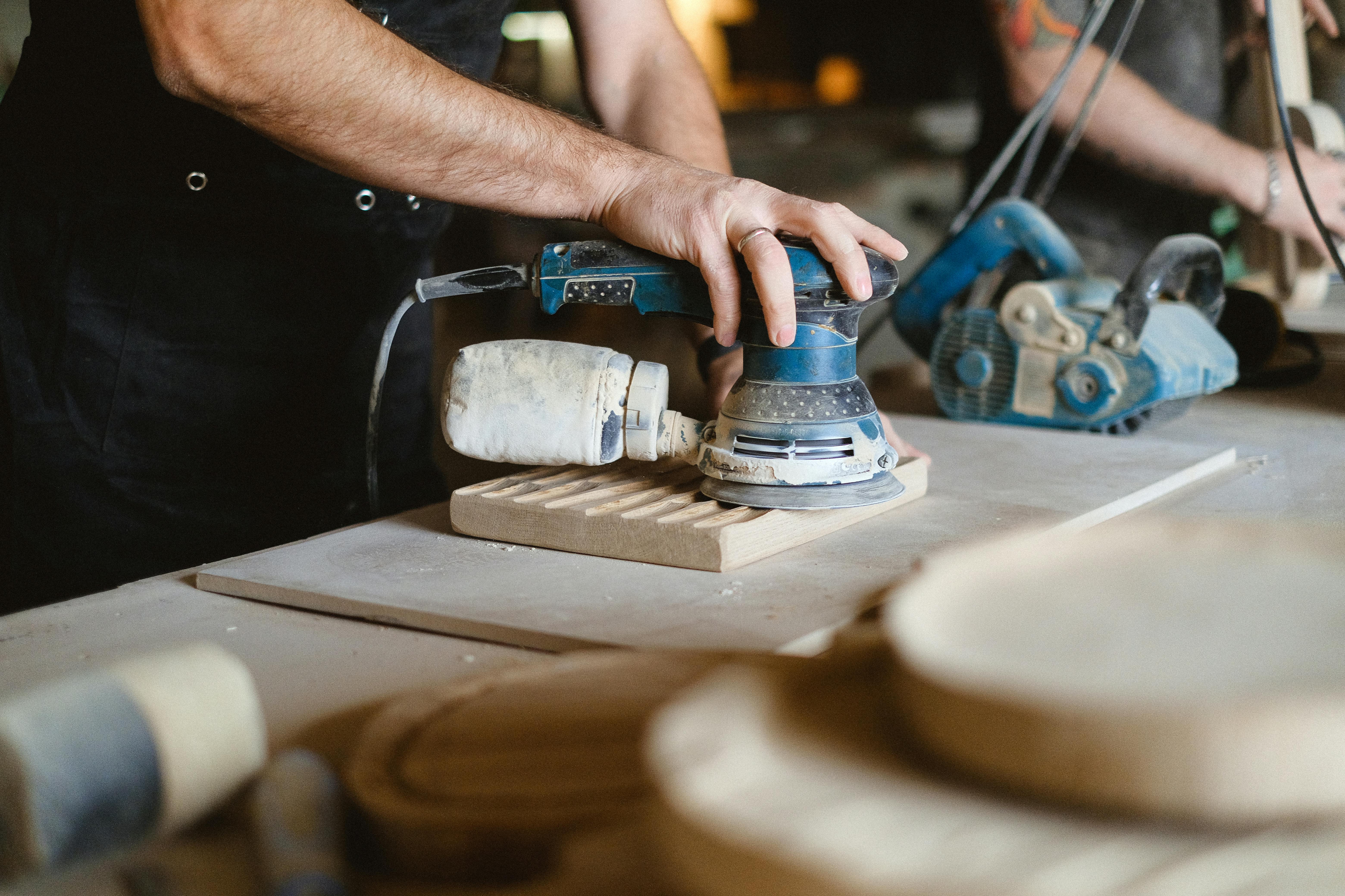 crop woodworker working with sander