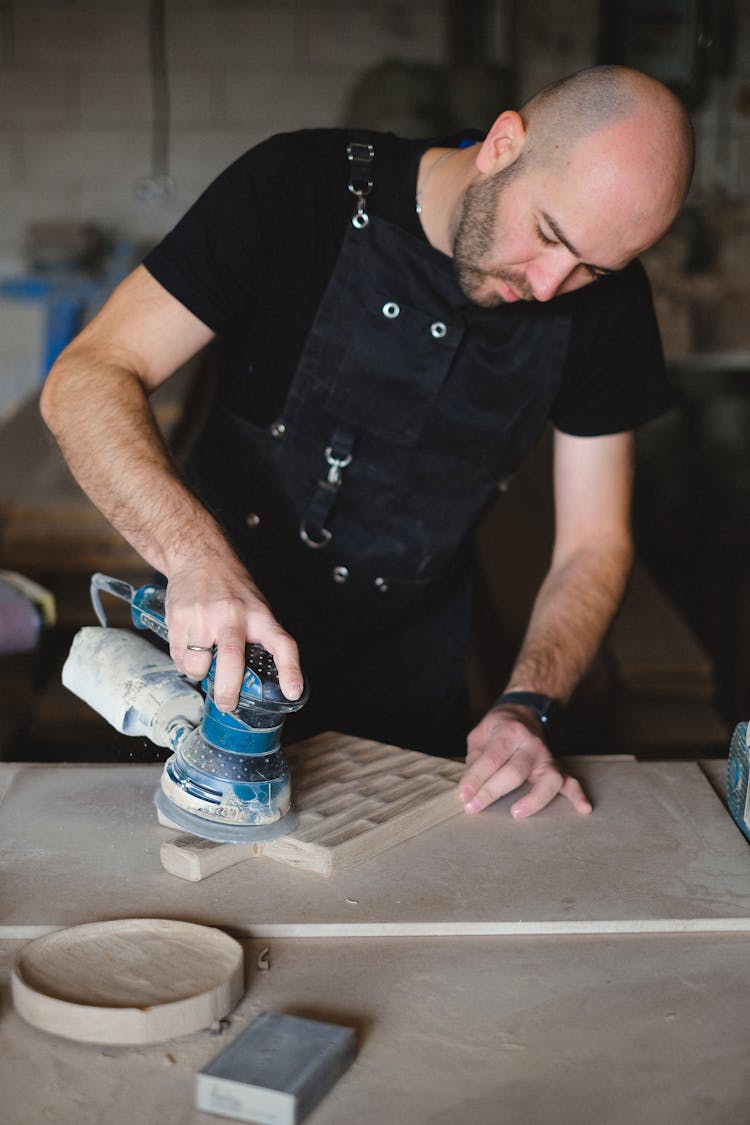 Craftsman Creating Wooden Board With Orbital Sander