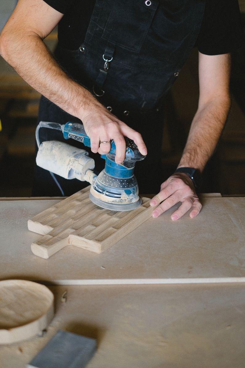 Craftsman sanding a tabletop with an electric sander