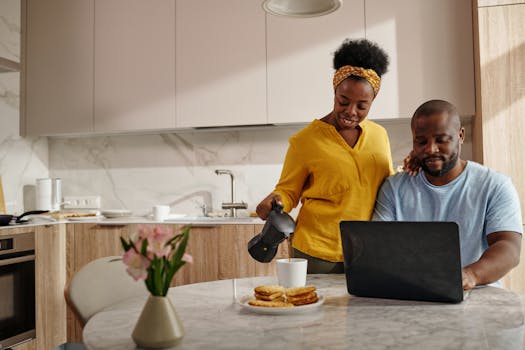 Smiling couple enjoying coffee and waffles at a dining table in a cozy kitchen setting.