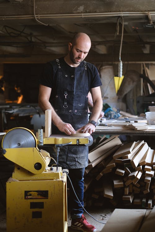 Skilled joiner using electric belt and disc sander