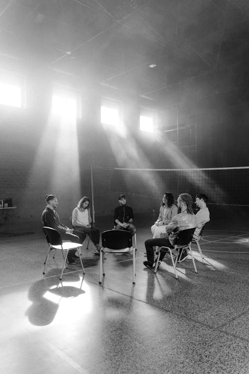 Grayscale Photo of People Sitting on Chairs